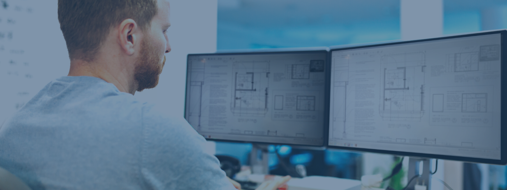 Employee reviewing building plans on desktop monitor